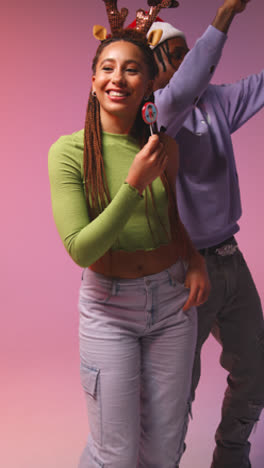 Foto-De-Estudio-De-Vídeo-Vertical-De-Amigos-De-La-Generación-Z-Bailando-En-Una-Fiesta-De-Navidad-Con-Gorro-De-Papá-Noel-Y-Astas-De-Reno-1